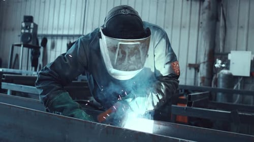 Professioneller Schweißer lötet Metallbalken in der Werkstatt