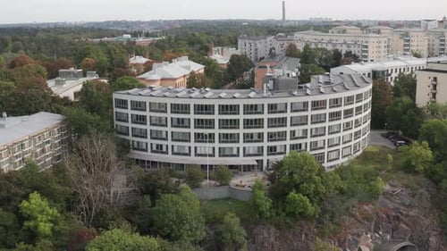 Drone footage circling of office building with solar panels on top with apartment buildings and vast