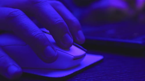 Homme utilisant une souris d'ordinateur lorsqu'il travaille au bureau en ligne la nuit