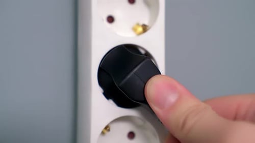 Plugging Black Electrical Plug into White Outlet Strip