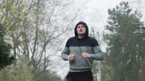Man Running in Rain Celebrates Victory in Park