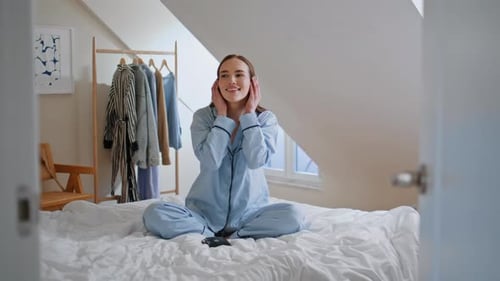 Woman in Pajamas Listening to Music on Bed
