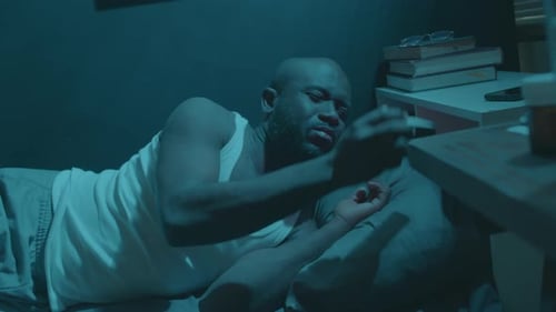 Man Lies in Bed in Dimly Lit Room