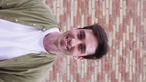 Porträt eines jungen erwachsenen Mannes, der in die Kamera lächelt und über dem Hintergrund der Stadtmauer steht