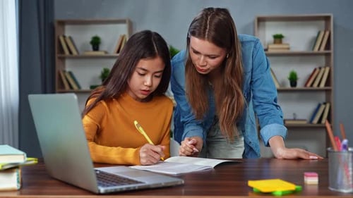 Woman and Teen Girl Studying Together at Home Table