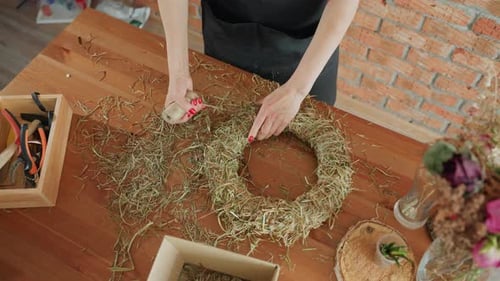 Woman Creates Rustic Wreath with Twine on Wood Table