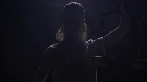 Backlit Statue of Lady Justice Holding Scales