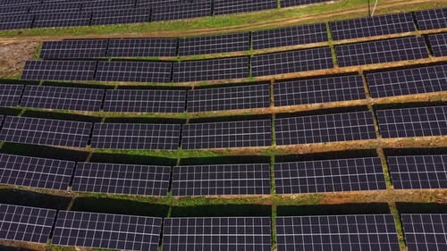 Solar panels create energy in a large solar farm under clear skies