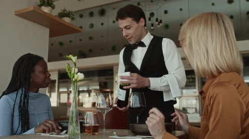 Sommelier Pouring Wine to Multiethnic Female Guests in Fine Dining Restaurant