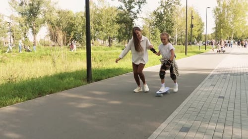 Girl Learning to Skateboard with Help of Friend