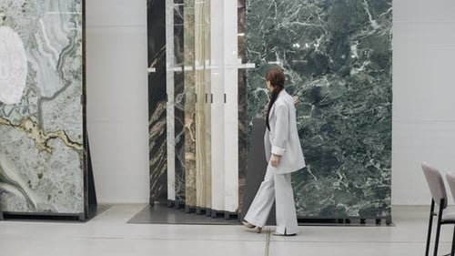 Woman walking in front of marble wall in tile showroom