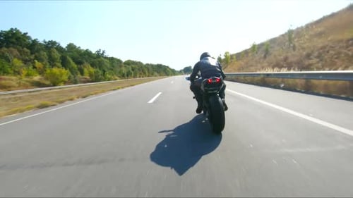 Biker is Driving Motorbike During Road Trip at Summer Day Man Ride Fast on Modern Sport Motorcycle