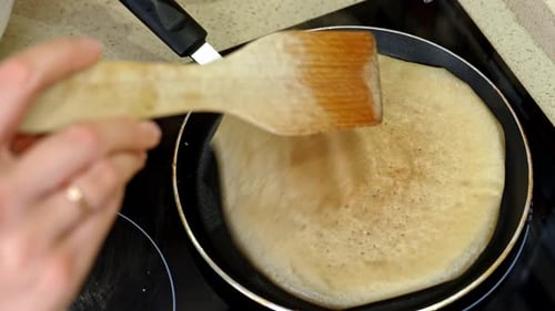 Pancake cooking on frying pan with spatula