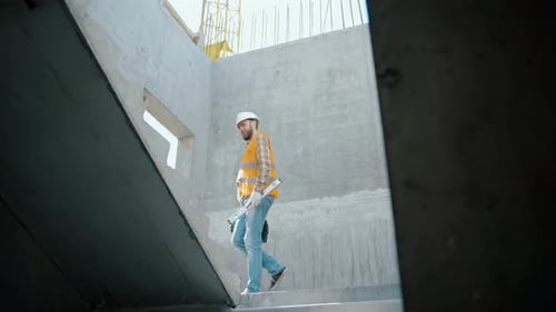 Construction Worker Ascending Concrete Staircase on Construction Site