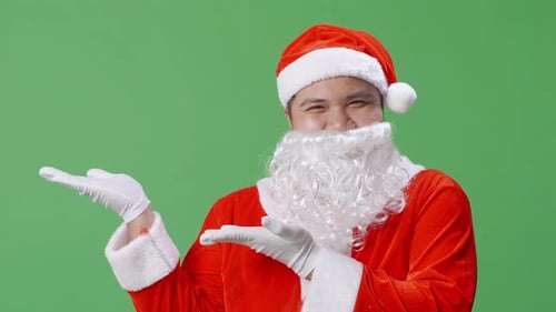 Close Up Of Asian Santa Claus Pointing To The Side While Standing On Green Screen In The Studio