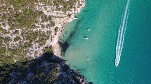 Boat drives past a beautiful beach.