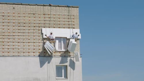 Construction Workers Repairing Brick Building