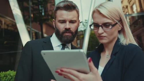 Colleagues Use Tablet Outside Modern Office Building