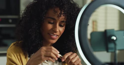 Retrato de una mujer sonriente del sudeste asiático grabando un vídeo tutorial de maquillaje con un teléfono inteligente en H