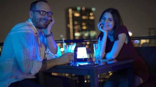 Portrait of Happy Couple with Cocktails Sitting on Terrace on Bar At