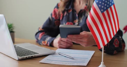 Woman Holds Passport Next to USA Flag and Application