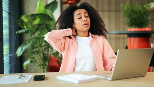 Professional Woman Suffering From Neck Pain While Working on Laptop in Office