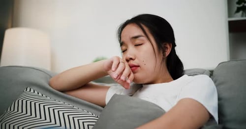 Young Woman Lounging Thoughtfully on Couch at Home
