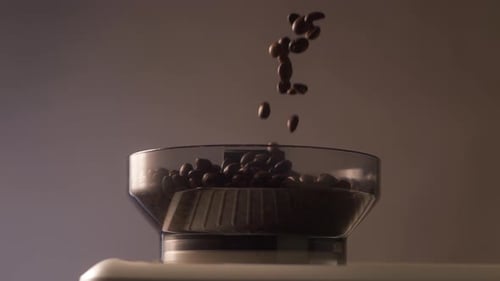 Kaffeebohnen fallen in Zeitlupe in den Mahlbehälter