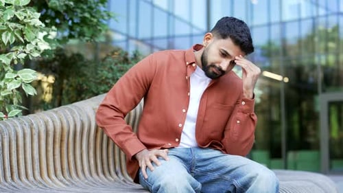Businessman has depression suffering from mental pain while sitting on a bench on the street near