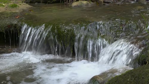 A small waterfall, water flowing over mossy rocks,close-up, clean water of a mountain stream