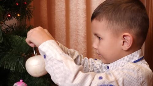 Boy Decorates Christmas Tree with White Ornament