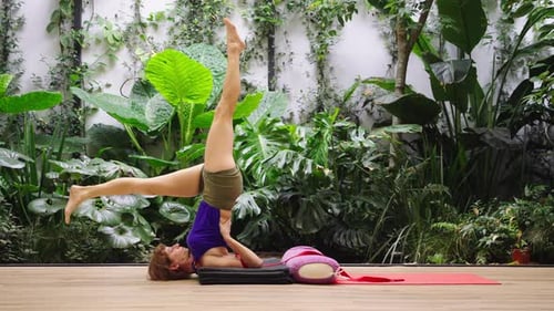 Woman Performs Shoulder Stand Yoga Pose Indoors
