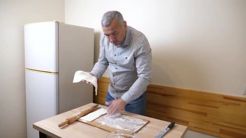 Man Prepares Dough with a Rolling Pin in Kitchen