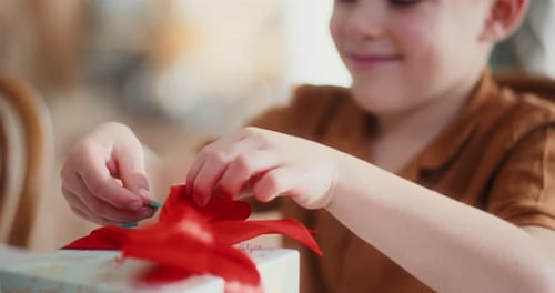 Excited Child Unwrapping Gift with Red Ribbon