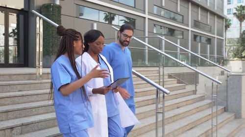 Video of Medical multiethnic team walking down hospital stairs discussing patient information