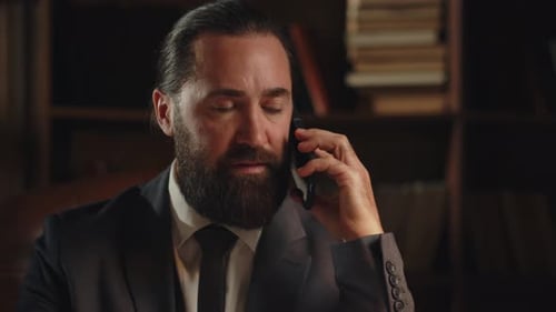 A Presentable Bearded Man Sitting in His Office Picks Up the Phone and Calls His Business Partner