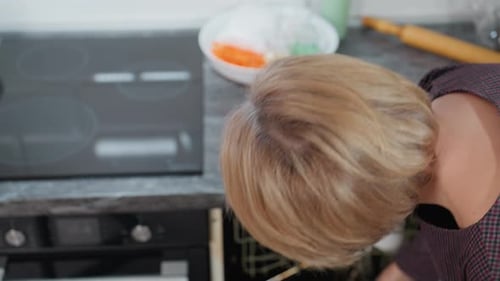 Woman Retrieving Pot From Cabinet to Place on Induction Stove in Modern Kitchen