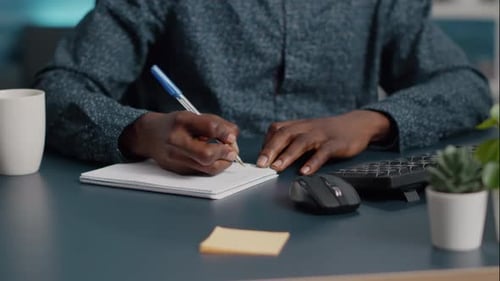 Close up of Right handed casual businessman writing daily tasks in organizer.