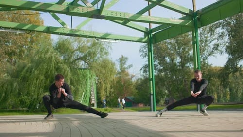 Men Stretching Outdoors Together in Urban Park Setting