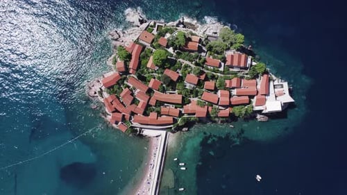 A drone flies over the island of Sveti Stefan on a sunny day in Montenegro