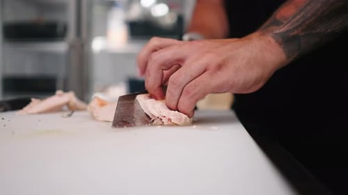Imagem aproximada de um chef profissional cortando carne de frango em uma tábua de cortar de restaurante