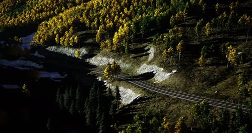 Estrada sinuosa pela floresta de outono com folhagem vibrante perto de uma montanha