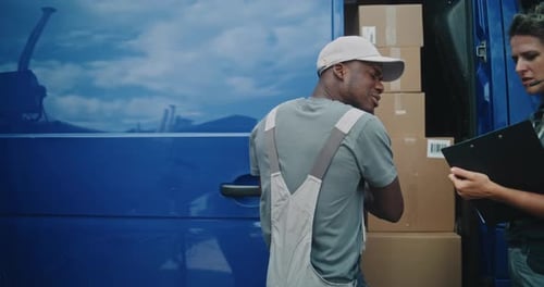 Employee Unloading Delivery Truck with Cardboard Boxes with Female Inventory Manager