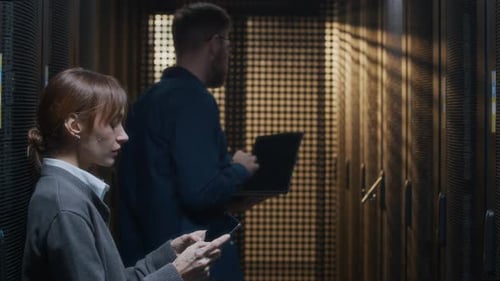 Young IT Technicians Inspecting Rack Server Cabinets in Data Center Together