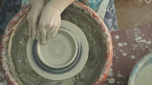 Mains d'une femme créant un pot en argile sur un tour de potier
