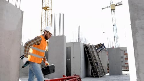 Construction Worker Walking with Tools on Site
