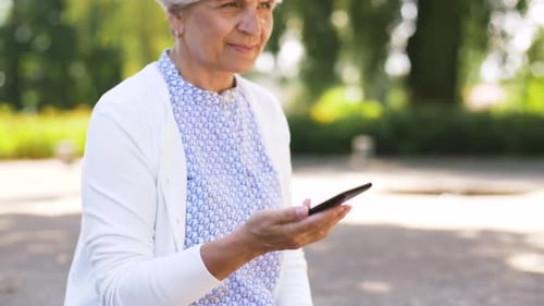 Smiling senior woman using phone in park