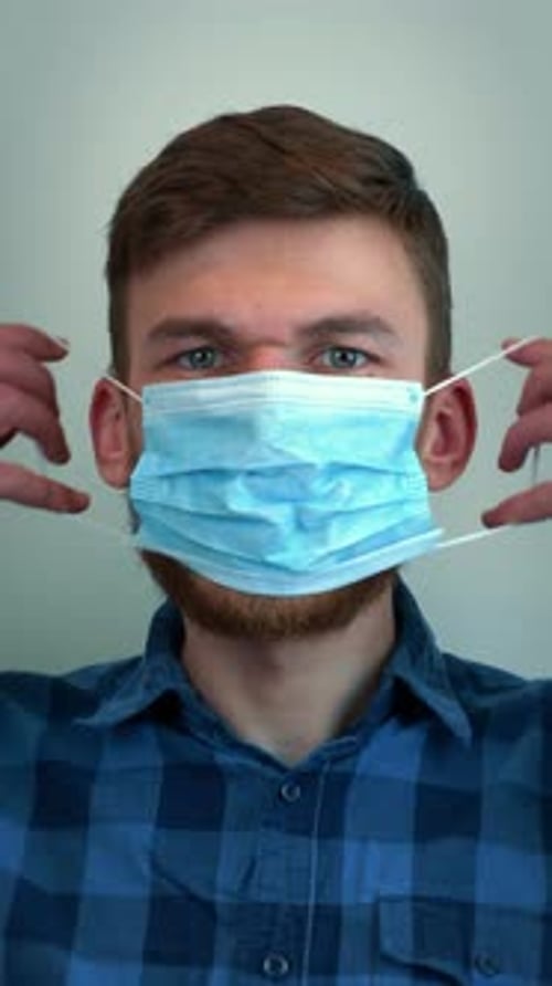 Young Adult Putting On a Surgical Face Mask