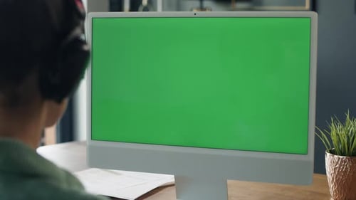 Rückansicht einer Frau, die am Computer mit grünem Bildschirm arbeitet. Aufgenommen mit der ROTEN Heliumkamera in 8K.