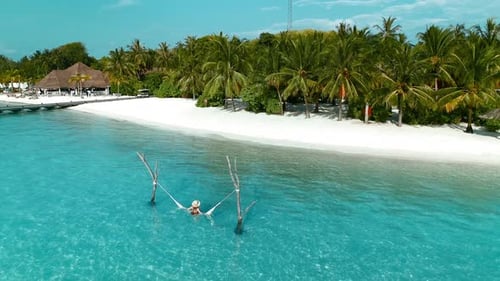 Aerial view of beautiful Maldives with woman relaxing in hammock, Laccadive Sea.